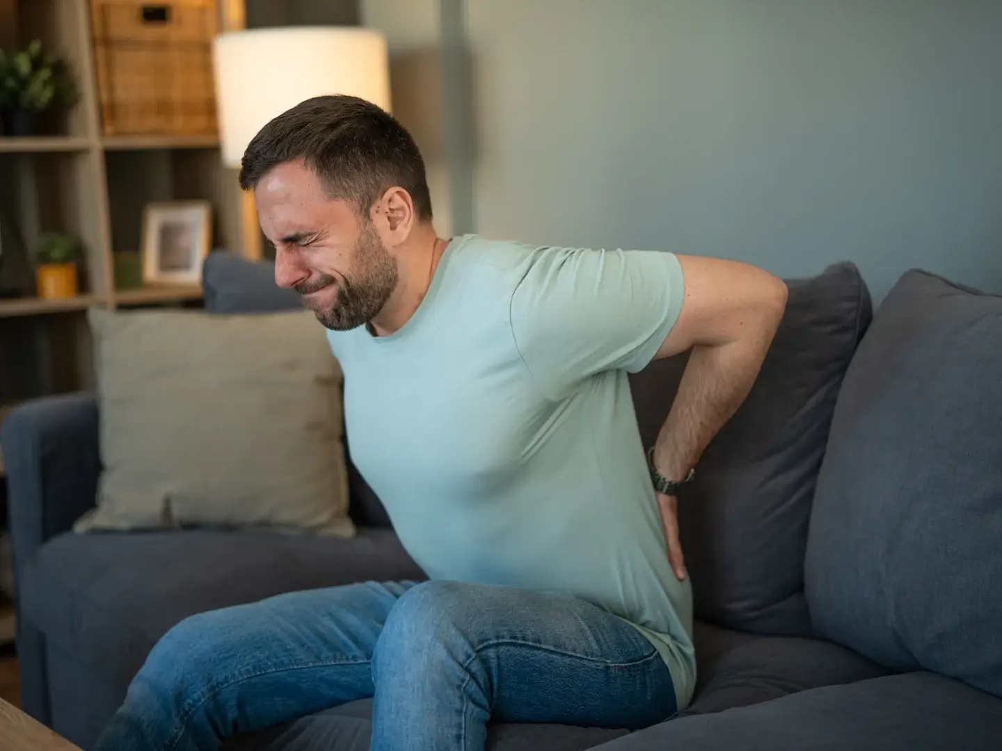 An adult holding their lower back while sitting